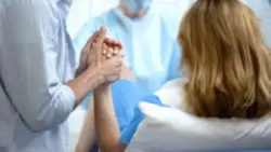 man holds woman’s hand as she gives birth