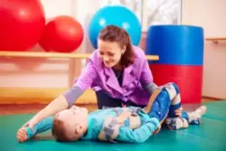 therapist performing musculoskeletal exercises on child with cerebral palsy