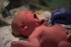 newborn baby crying as doctor listens to heartbeat