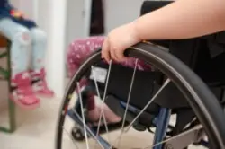 close-up of child’s hand on wheelchair wheel
