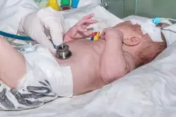 doctor using stethoscope to conduct check-up on newborn