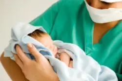 maternity nurse holding newborn in blanket