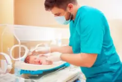 nurse tending to newborn in nicu incubator