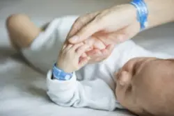 A mother holds her infant’s hand in the hospital.