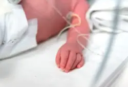 infant’s hand lies among tubes