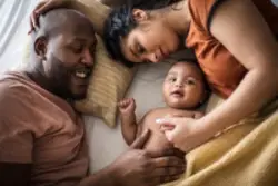 mother and father lie in bed with baby