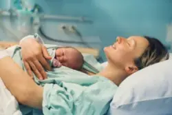 mother holds newborn baby in hospital bed