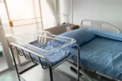 empty hospital bassinet beside hospital bed