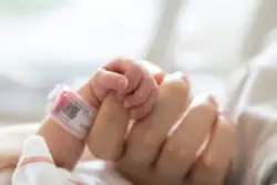 A newborn baby holds her mother’s hand. Contact an Atlanta birth injury lawyer now.