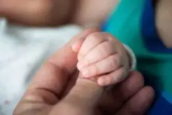 A baby holds the finger of an Atlanta brachial plexus birth injury lawyer.