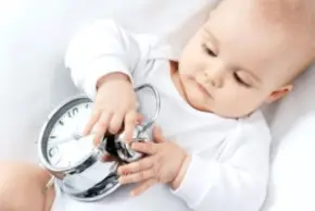 A baby is holding a clock, symbolizing the statute of limitations for cerebral palsy cases.