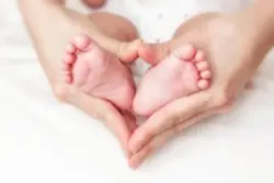 A cerebral palsy lawyer in Arizona holds a baby's feet in her hands.