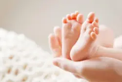 A cerebral palsy lawyer in Illinois holds a baby's feet.