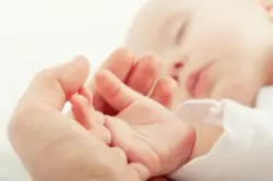 A cerebral palsy lawyer in Kentucky holds the hand of a newborn diagnosed with cerebral palsy.