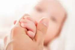A cerebral palsy lawyer in Minnesota holds the hand of a baby diagnosed with cerebral palsy.