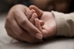 A cerebral palsy lawyer in Pennsylvania holds the hand of a baby diagnosed with a birth injury.