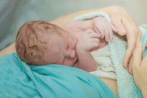 Mother cradling newborn baby suffering from long-term side effects of Pitocin