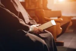 A clergy member holds a bible after a victim has proven clergy abuse.