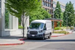 A white delivery truck sits on the side of the road.