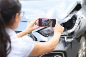 A woman using a smartphone to take photos of damage to her car as she deals with the aftermath of an accident with a Prime Inc. truck in Dayton.