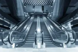 Las Vegas Escalator Accident Lawyer: Symmetrical view of escalators in a modern building, with a blue tone
