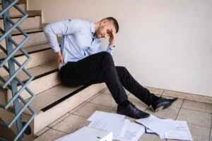 A man who fell on the stairs holding his back wondering how negligence is proven in a slip and fall claim.