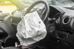 the interior of a car showing a deployed airbag after an accident