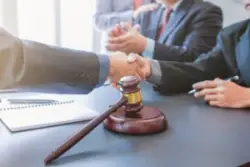 men in suits shaking hands next to a gavel