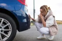 A woman assesses damage and wonders, “Should I hire a car accident lawyer for a minor accident?
