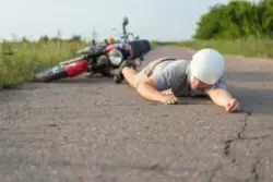 Man wearing helmet lies on ground near motorcycle after accident in Bridgeport