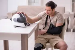 A man wears a sling and knee brace after a motorcycle accident.