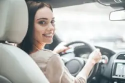 A woman smiles while driving before calling a Windsor car accident lawyer.