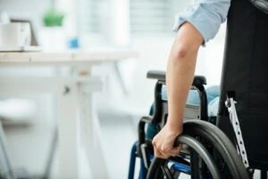 Woman in wheelchair next to an office desk hand close up unrecognizable person