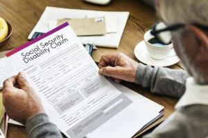 A man looks at a Social Security Disability claim form. Learn how long it could take you to resolve an SSD appeal case and how a lawyer can help you.