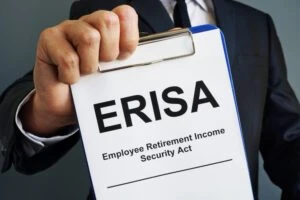 A man holds a notepad with a page that says ERISA on it. Find out how the ERISA disability claims process works and how a lawyer can help with your case.