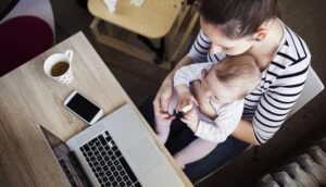 A woman sits at a desk with a baby on her lap while on maternity leave. You can review your options with a lawyer to find out if your Short Term Disability policy covers maternity leave.