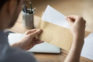 A man opens up an envelope to see if he is eligible to receive Supplemental Security Income (SSI) benefits. Talk with an attorney if you have questions about how much money you can make and still get SSI.