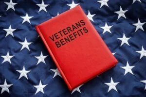 A red “Veterans Benefits” book lays on an American flag, prompting the question: What Is TDIU? How do you qualify, and what are the benefits?