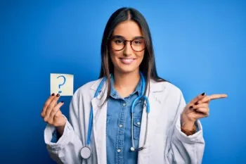 A doctor holding a paper with a question mark on it and pointing to her left represents an answer to the question of whether the reader should go to the ER after a car accident.