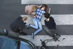 Injured Woman Lying In The Crosswalk With People Helping Her