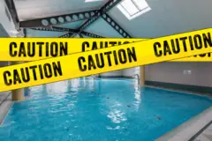 yellow caution tape in front of a swimming pool due to an accident
