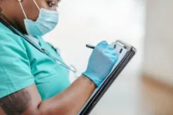 African American nurse writing on a clipboard