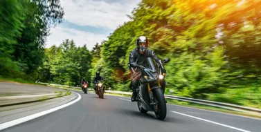 3 motorcycles going around a bend surrounded by trees