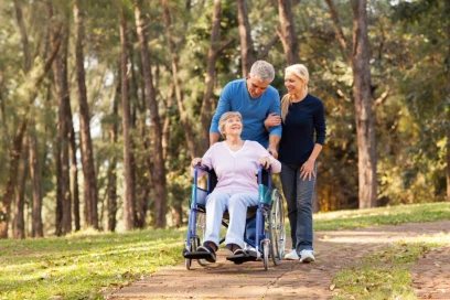 elderly woman being pushed in wheelchair by family