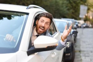 A man with his head out of the window, yelling. How can I identify signs of aggressive driving before it escalates?
