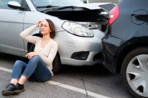 An injured woman holding her head after a rear-end collision on a highway.