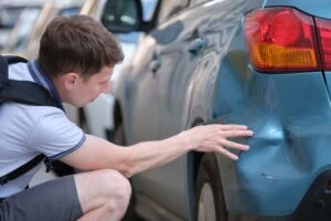A man examining the damage after a hit-and-run incident. What should you do immediately?