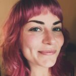 Women with purple hair smiling at camera