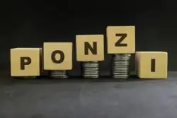 Stacks of coins with wooden block cubes spelling out the word Ponzi on a Michigan Ponzi scheme lawyers' desk.