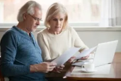 An older couple looks at their retirement fund on a computer and wonders, “What happens to my stock if a brokerage firm fails?”